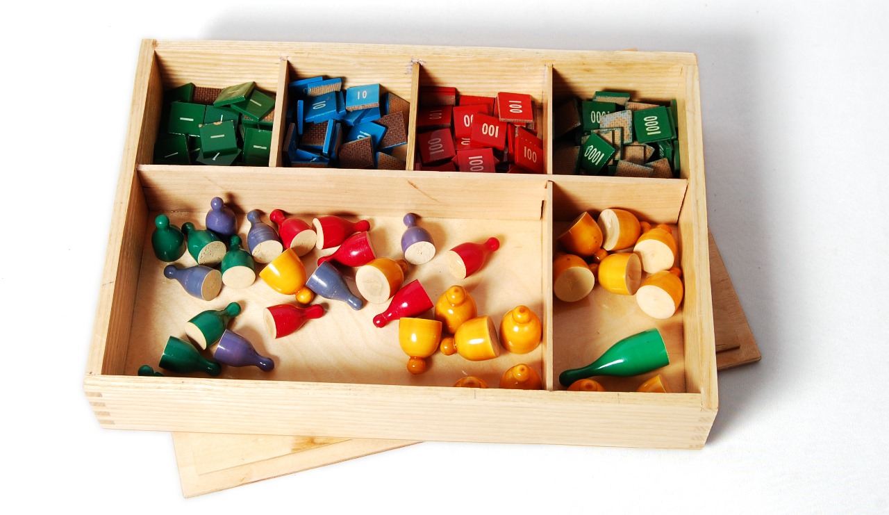 STAMP GAME(A WOODEN BOX WITH COMPARTMENTS CONTAINING  WOODEN STAMPS FOR UNITS ,TENS ,HUNDREDS AND THOUSANDS AND WITH FEW SKITTLES)